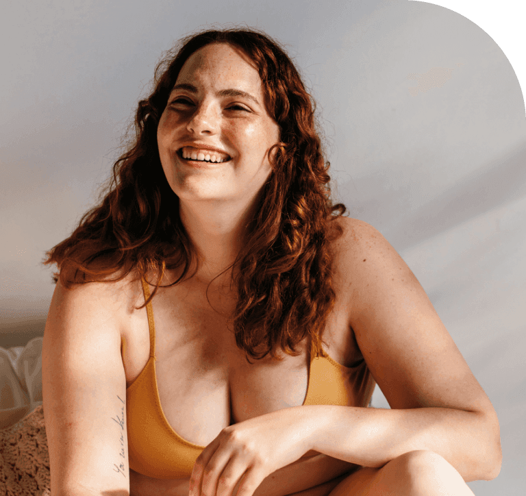 Smiling woman sitting casually, representing a positive and welcoming start to a personalized health and wellness journe